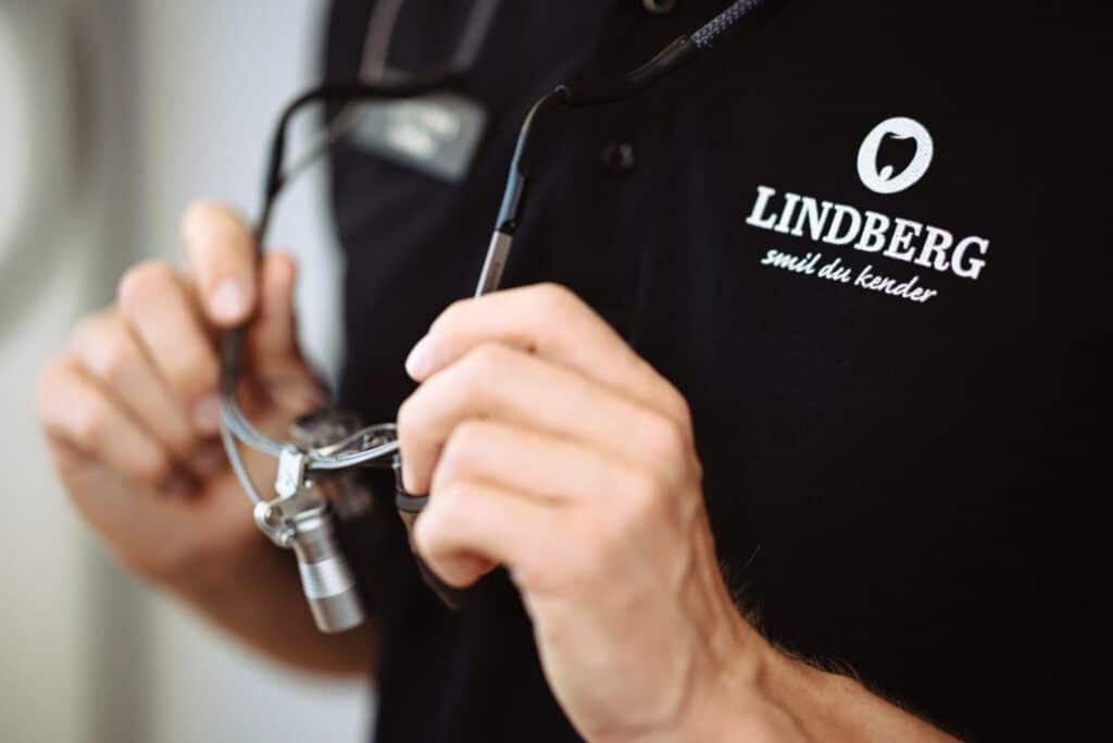 Et nærbillede af en medarbejder fra Lindberg Tandlægeklinik. Vedkommende har et stetoskop om halsen